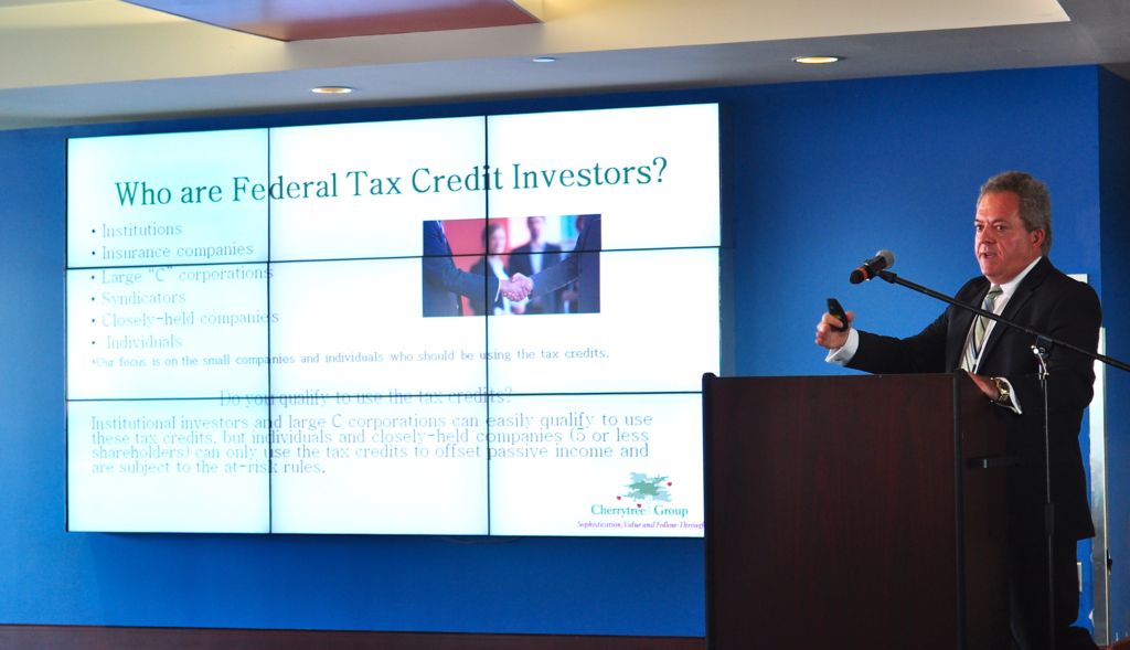 Warren Kirshenbaum speaking at a conference with Who are Federal Tax Credit Investors slide in background.